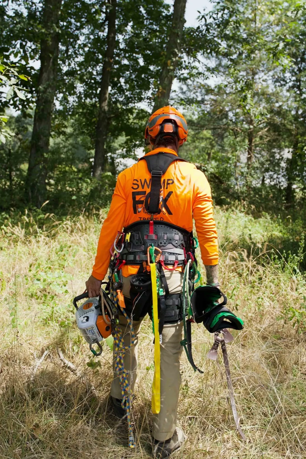 Swamp Fox Tree Co. climber in gear walking toward a job site